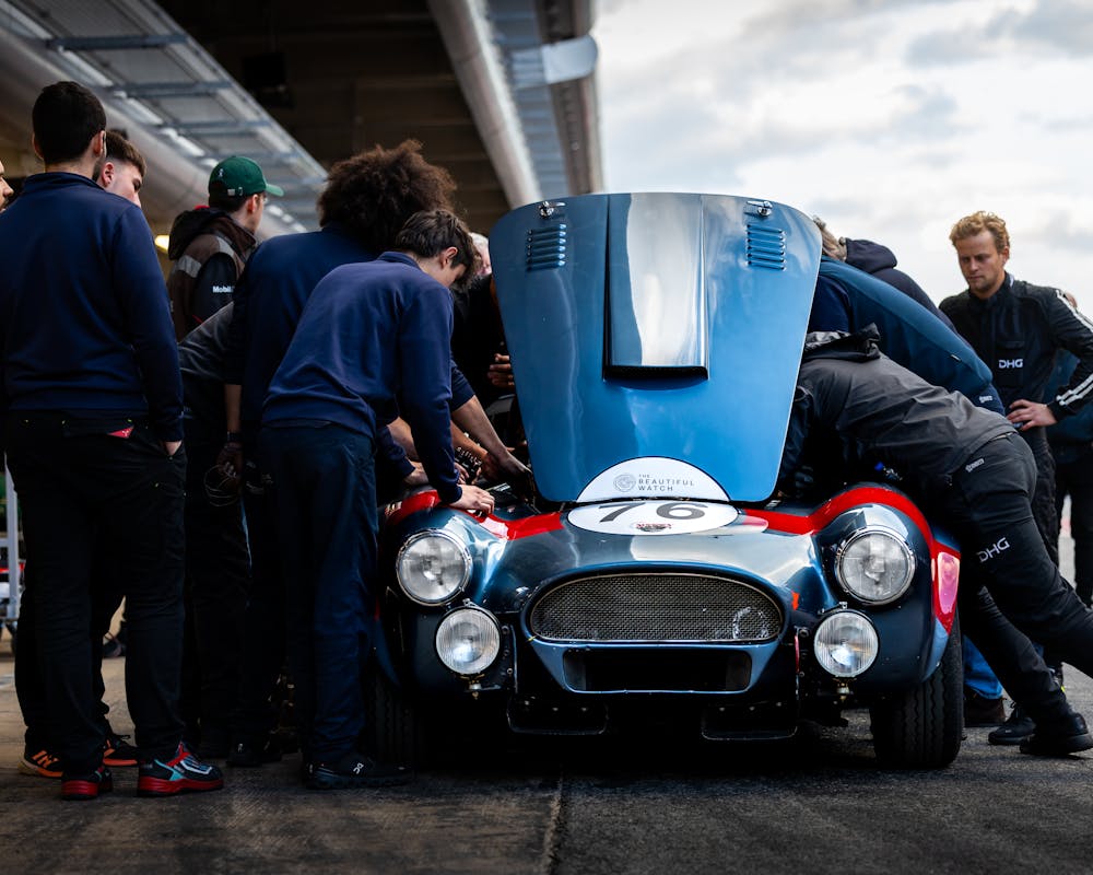 A race team working on a classic competition car in the pit lane